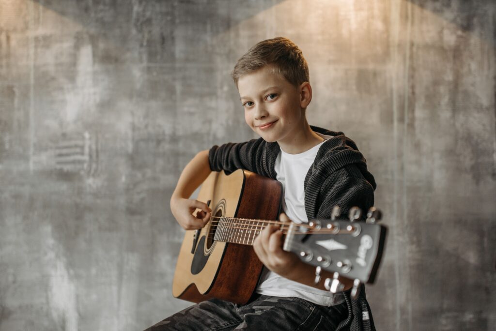 Niño aprendiendo a tocar la guitarra clásica en clase